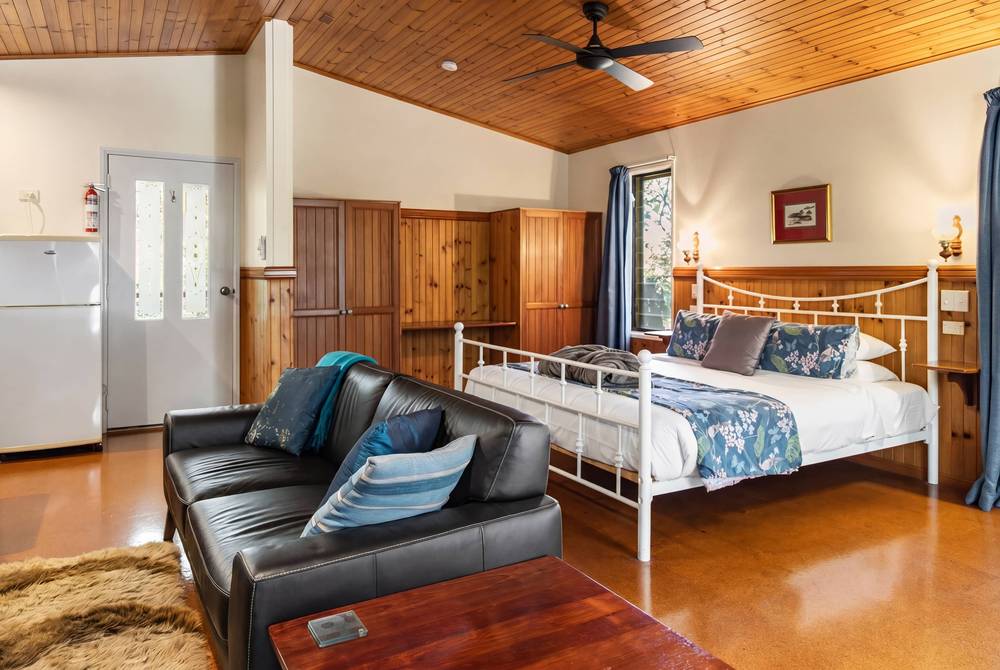 Cabin bedroom with metal bed frame, wooden cabinetry and TV