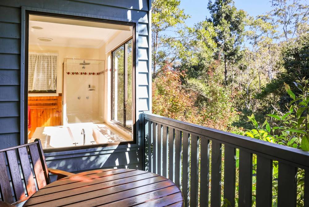 Cabin deck with spa bath, lounger and bushland view beyond