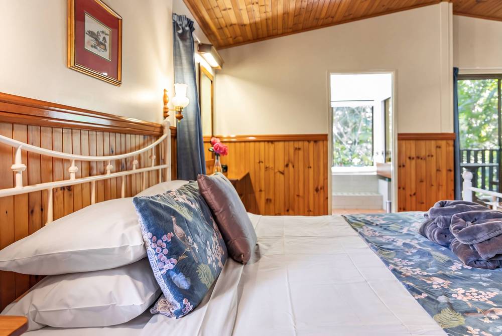 Bedroom with timber headboard, forest views and rainfall showerhead