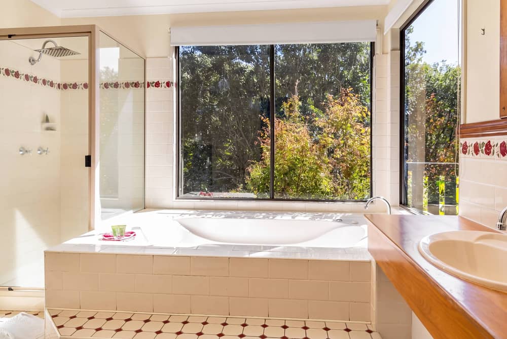 Spa bath beside a large window overlooking rainforest