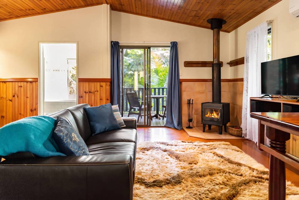 Living area with charcoal sofa, wood-burning stove and solid timber floor