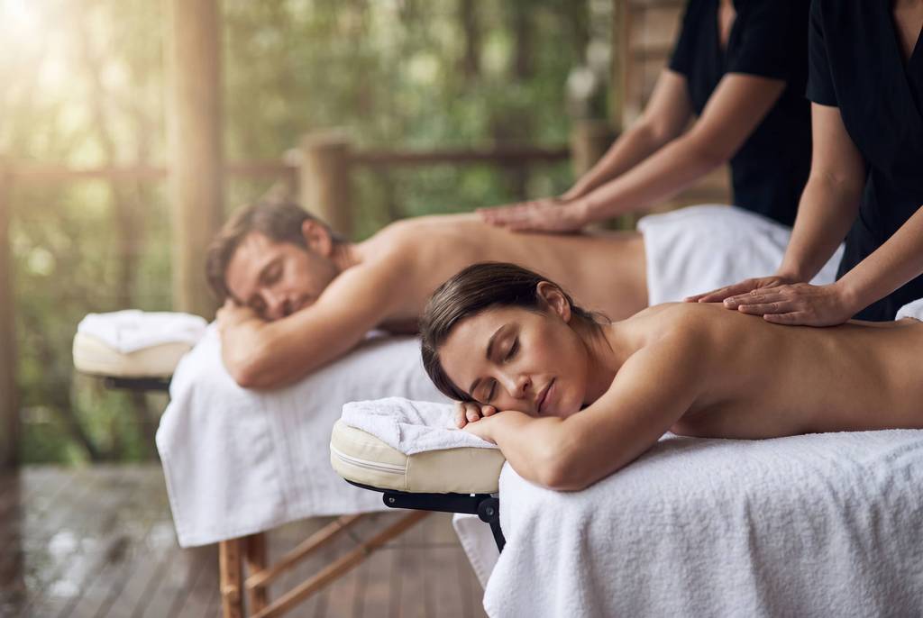A couple enjoying a side-by-side massage on a rainforest-view balcony