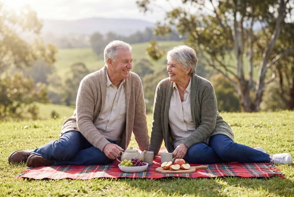 Couple sitting on a picnic blanket with refreshments and a hinterland view