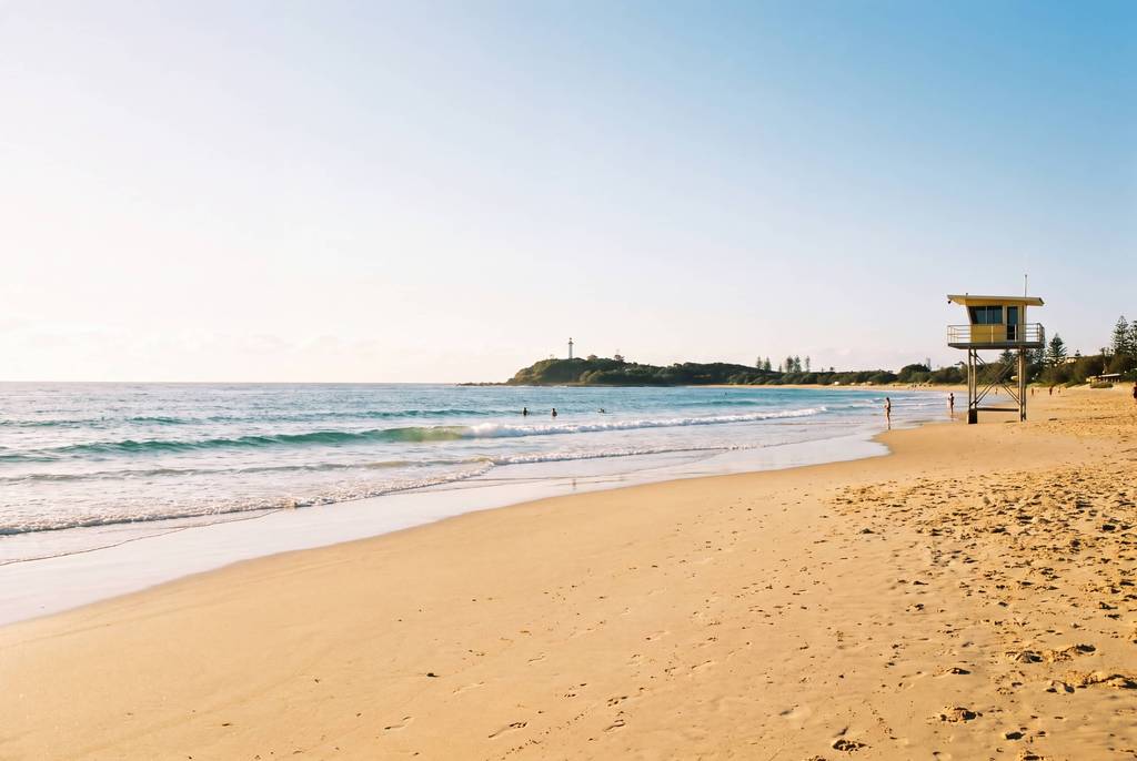 Sandy beach, surf and lifeguard tower near a coastal headland