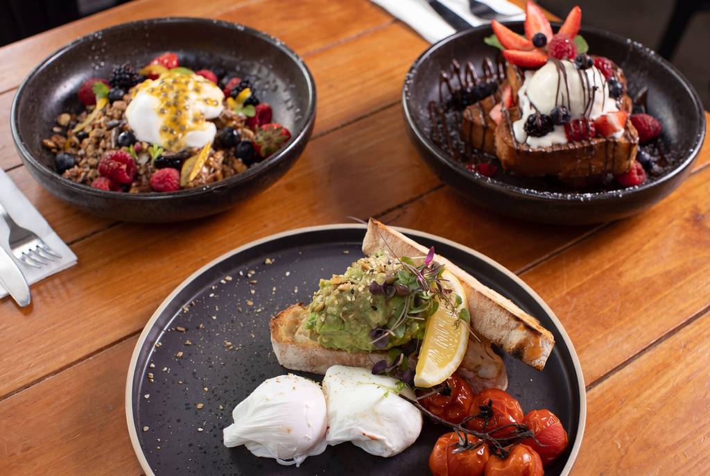 Restaurant dishes with fresh berries and cream on a wooden deck table